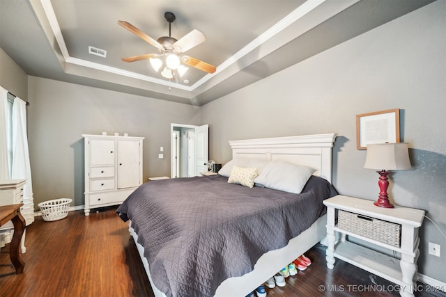 bedroom featuring ceiling fan, dark hardwood / wood-style floors, and a raised ceiling