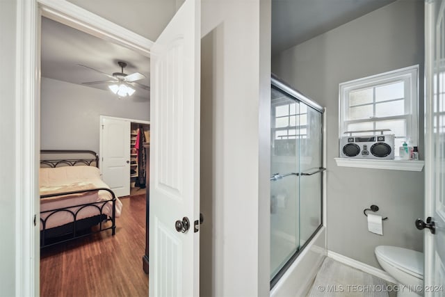 bathroom featuring wood-type flooring, toilet, enclosed tub / shower combo, and ceiling fan