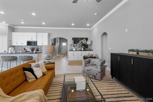 living room featuring ornamental molding, ceiling fan, sink, and light hardwood / wood-style flooring