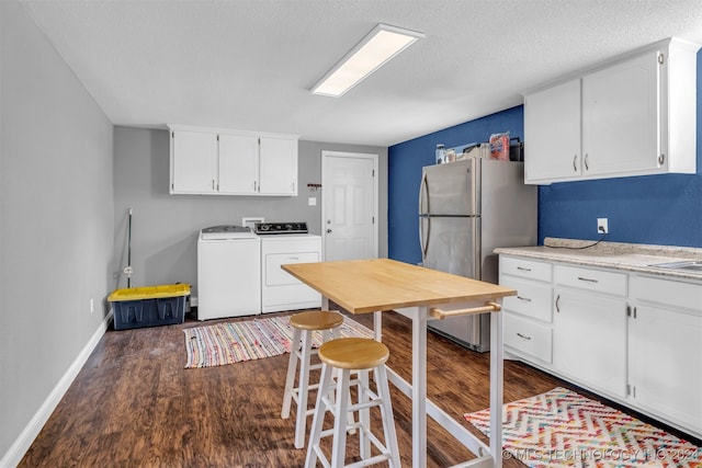 kitchen with independent washer and dryer, dark wood-type flooring, stainless steel refrigerator, white cabinetry, and a textured ceiling