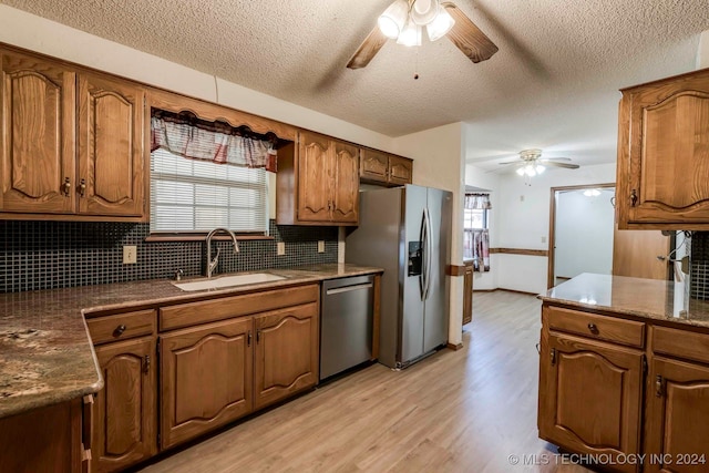 kitchen featuring appliances with stainless steel finishes, a wealth of natural light, sink, and light hardwood / wood-style flooring