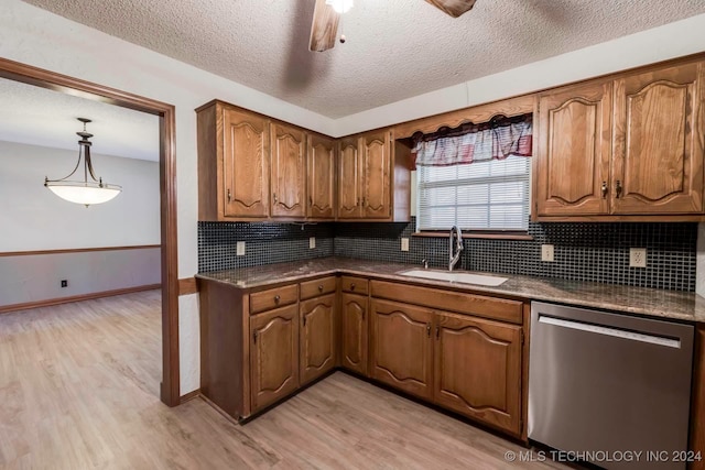 kitchen with sink, hanging light fixtures, stainless steel dishwasher, and light hardwood / wood-style floors