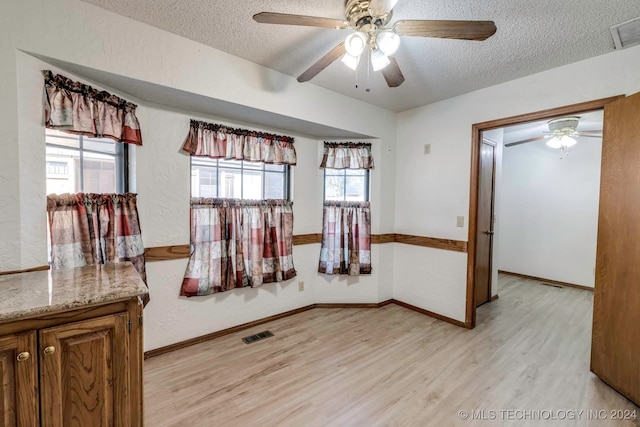 interior space featuring ceiling fan, light wood-type flooring, and a textured ceiling