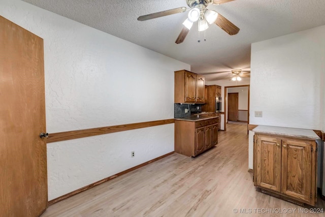 kitchen with a textured ceiling, light hardwood / wood-style floors, oven, and decorative backsplash