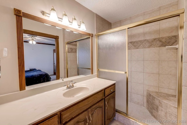 bathroom with an enclosed shower, ceiling fan, vanity, and a textured ceiling