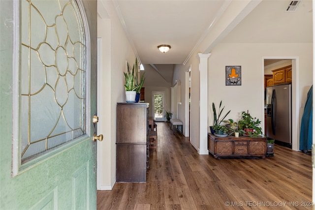 corridor featuring ornamental molding, decorative columns, and dark wood-type flooring