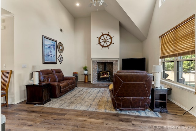 living room featuring a wood stove, high vaulted ceiling, ceiling fan, and hardwood / wood-style floors