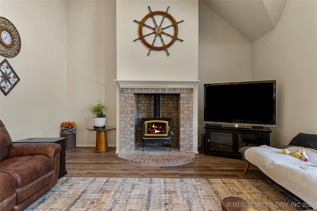 living room with high vaulted ceiling, hardwood / wood-style floors, and a wood stove