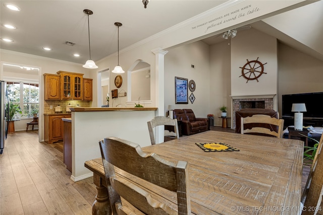 dining area featuring ornate columns, crown molding, and light hardwood / wood-style flooring