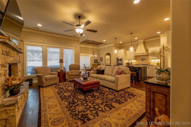 living room with ceiling fan with notable chandelier, ornamental molding, and dark hardwood / wood-style floors