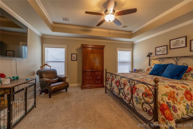 bedroom with crown molding, ceiling fan, a tray ceiling, and light colored carpet