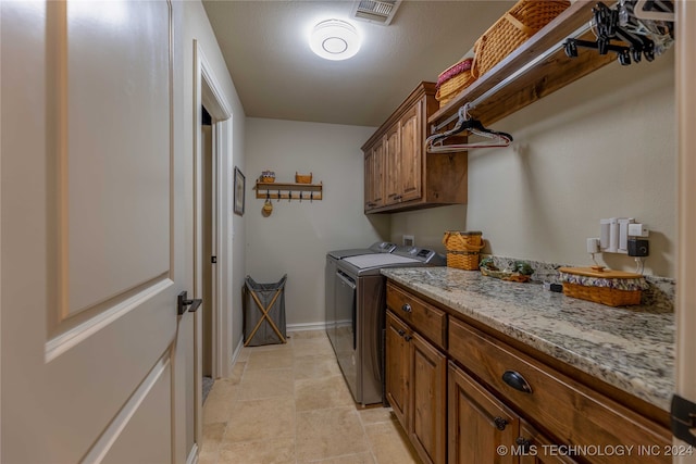 laundry area featuring light tile patterned flooring, washer and dryer, and cabinets