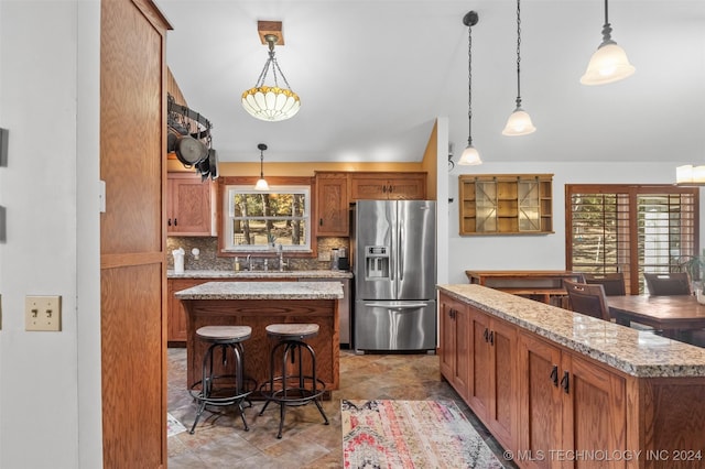 kitchen with stainless steel fridge, a center island, hanging light fixtures, and a healthy amount of sunlight