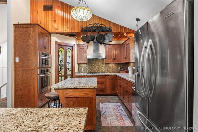 kitchen featuring wall chimney exhaust hood, appliances with stainless steel finishes, tasteful backsplash, decorative light fixtures, and a kitchen island