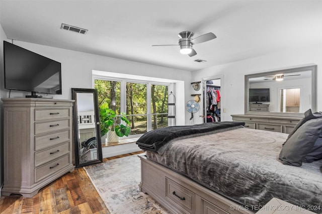 bedroom with ceiling fan, dark hardwood / wood-style floors, a walk in closet, and a closet