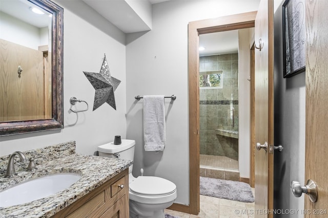 bathroom with tile patterned floors, toilet, a tile shower, and vanity