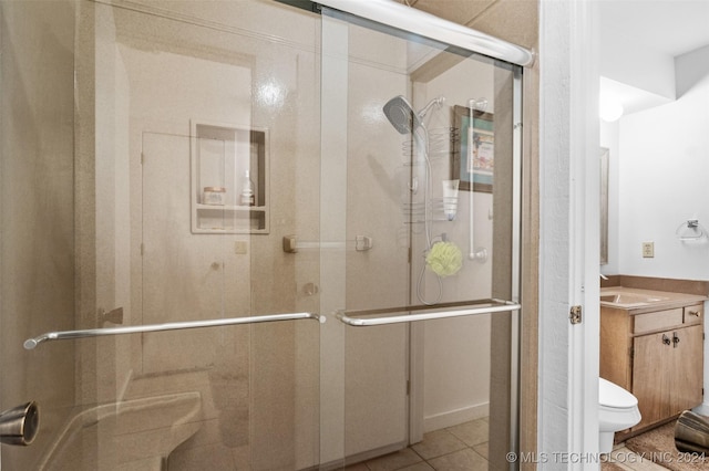 bathroom with tile patterned floors, vanity, a shower with shower door, and toilet