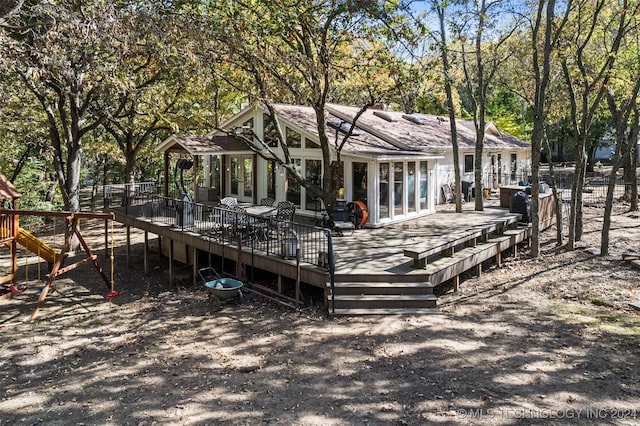 rear view of house featuring a playground and a deck