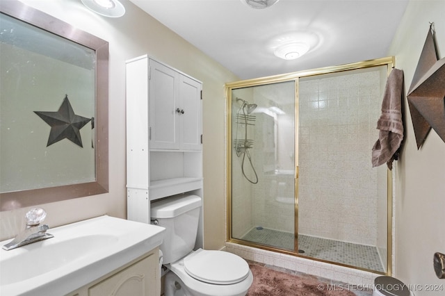 bathroom featuring vanity, toilet, and a shower with shower door