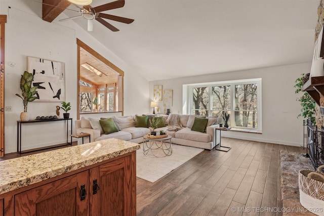 living area with dark wood-type flooring, lofted ceiling, a healthy amount of sunlight, and a fireplace