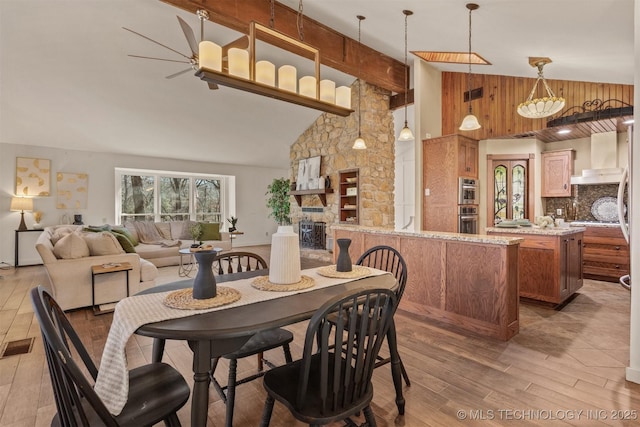 dining area with high vaulted ceiling, a fireplace, wood finished floors, and visible vents