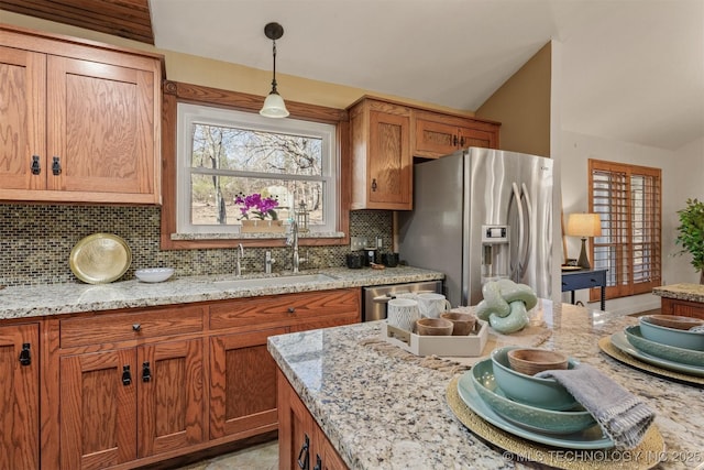 kitchen featuring decorative backsplash, lofted ceiling, hanging light fixtures, stainless steel appliances, and a sink