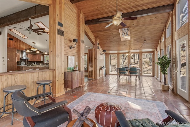 tiled living room featuring wooden ceiling, ceiling fan, wooden walls, and beamed ceiling