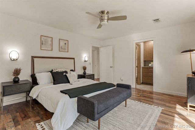 bedroom with visible vents, ensuite bathroom, a ceiling fan, wood finished floors, and baseboards