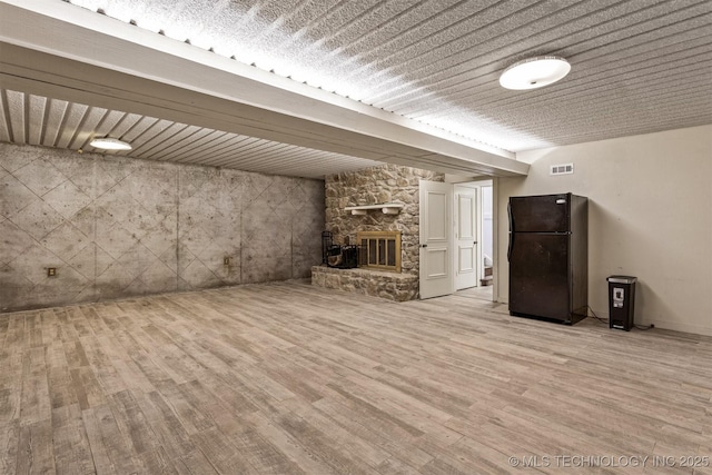 unfurnished living room featuring a fireplace, wood finished floors, and visible vents