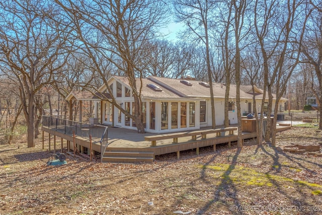 rear view of house featuring a shingled roof, fence, and a deck