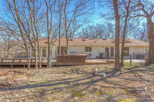 rear view of property with a wooden deck, a chimney, fence, and stucco siding