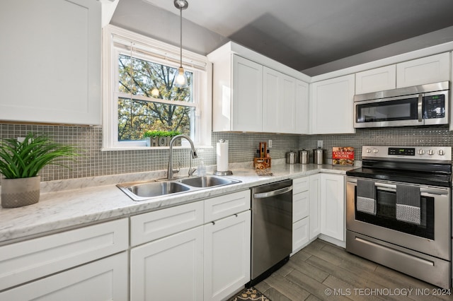 kitchen with hanging light fixtures, white cabinetry, sink, and stainless steel appliances