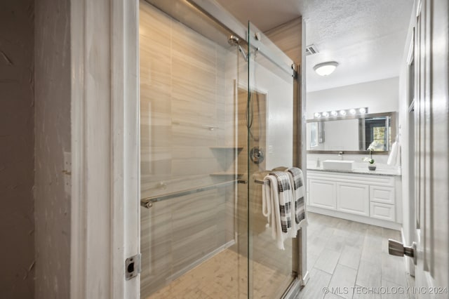 bathroom with vanity, a textured ceiling, and an enclosed shower