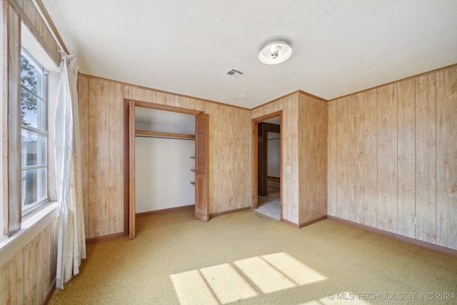 unfurnished bedroom featuring carpet flooring, a closet, and wood walls