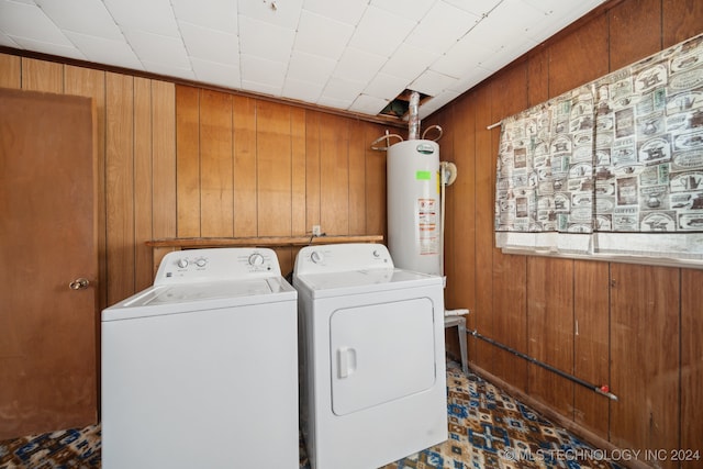 washroom featuring wooden walls, washer and clothes dryer, and water heater