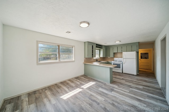 kitchen featuring green cabinetry, kitchen peninsula, hardwood / wood-style flooring, and white appliances