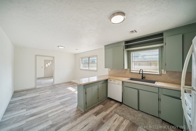 kitchen with kitchen peninsula, sink, white appliances, and a wealth of natural light