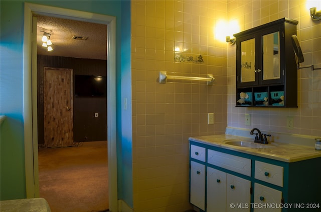 bathroom with tile walls, vanity, decorative backsplash, and a textured ceiling