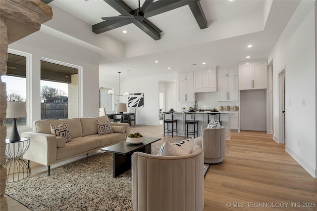 living room featuring sink, light hardwood / wood-style floors, and ceiling fan with notable chandelier