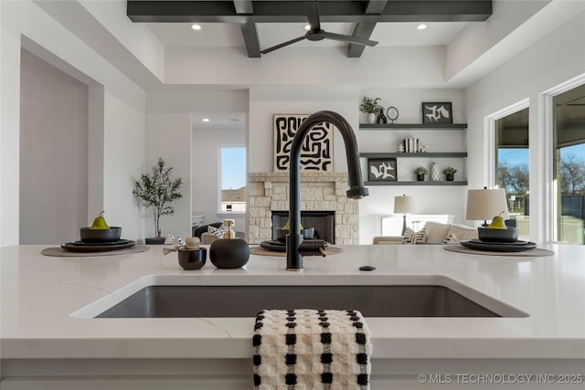 kitchen featuring a stone fireplace, a wealth of natural light, sink, and coffered ceiling