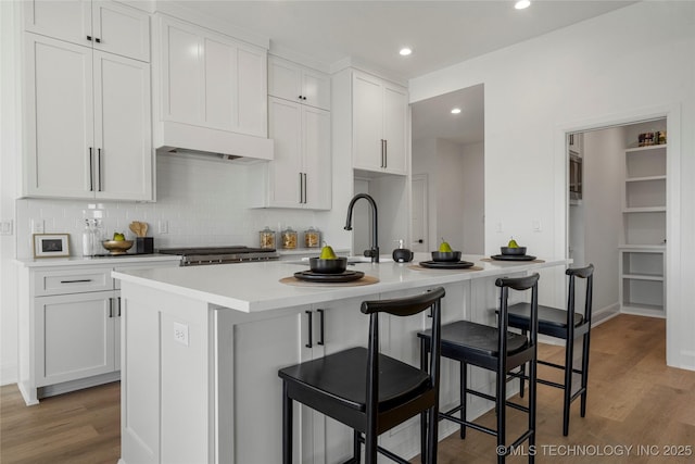 kitchen with white cabinets, a kitchen bar, and a kitchen island with sink