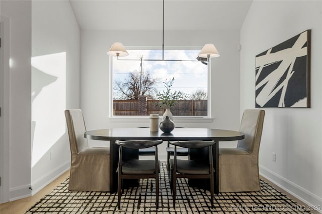 dining room featuring hardwood / wood-style flooring and vaulted ceiling