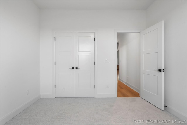 unfurnished bedroom featuring light colored carpet and a closet