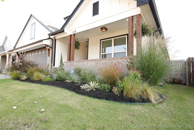 view of front of home featuring a porch, a garage, and a front yard