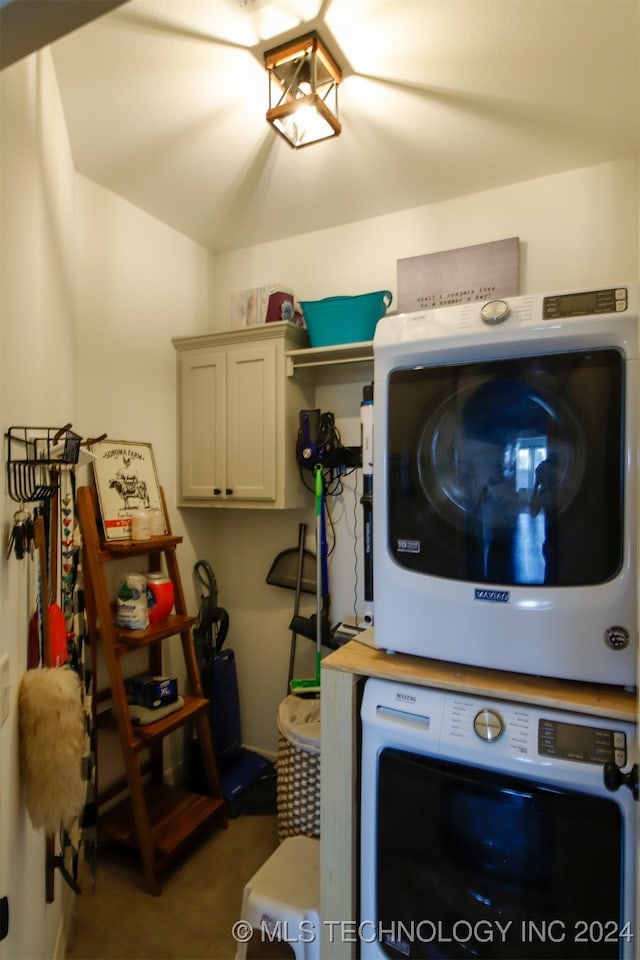 laundry room featuring cabinets and stacked washer and clothes dryer