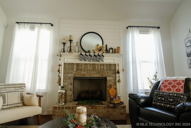 living area with hardwood / wood-style flooring and a brick fireplace