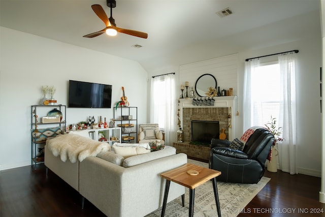 living room featuring a brick fireplace, dark hardwood / wood-style floors, vaulted ceiling, and ceiling fan