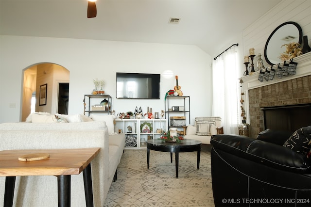 living room featuring ceiling fan, lofted ceiling, and a fireplace