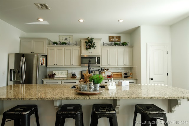 kitchen with a breakfast bar area, a large island, light stone countertops, and stainless steel appliances