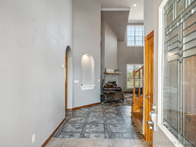 tiled foyer entrance with a high ceiling and a brick fireplace